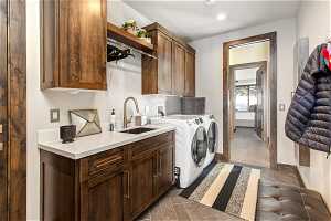 Washroom featuring cabinets, dark tile flooring, washer hookup, washer and clothes dryer, and sink