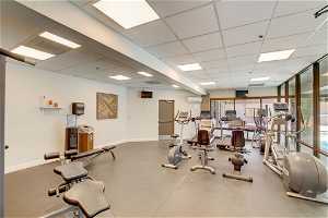 Exercise room featuring a drop ceiling and an AC wall unit