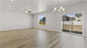 Empty room featuring light hardwood / wood-style flooring and ceiling fan with notable chandelier