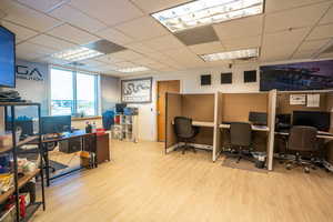 Office space with a paneled ceiling and light hardwood / wood-style floors