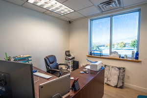 Office featuring light wood-type flooring and a paneled ceiling