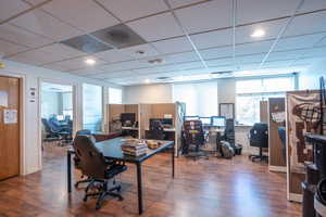 Office area featuring dark wood-type flooring and a paneled ceiling