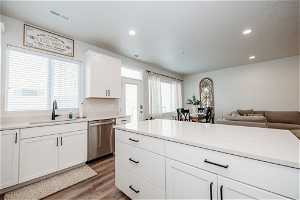 Kitchen featuring sink, white cabinets, stainless steel dishwasher, and light hardwood / wood-style floors