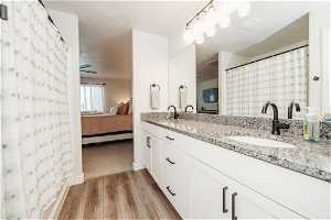 Bathroom with wood-type flooring, dual sinks, ceiling fan, and oversized vanity
