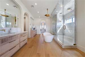 Bathroom with wood-type flooring, vanity with extensive cabinet space, and plus walk in shower
