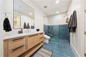Bathroom with vanity, toilet, tile flooring, and a shower with door