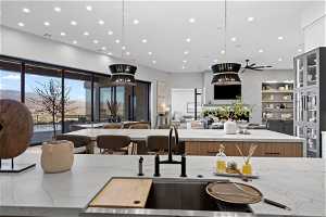 Kitchen with ceiling fan, light stone countertops, a center island, and decorative light fixtures