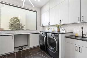 Laundry room featuring separate washer and dryer, cabinets, sink, and dark tile floors