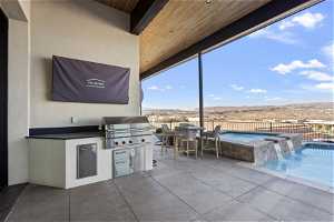 View of patio with pool water feature, exterior kitchen, a grill, and a pool with hot tub