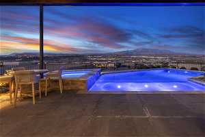 Pool at dusk featuring an in ground hot tub, a patio, and a mountain view