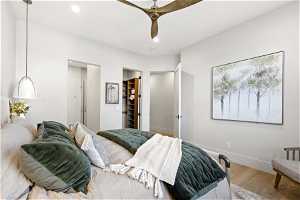 Bedroom with light hardwood / wood-style floors, a closet, a walk in closet, and ceiling fan