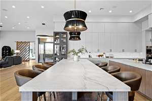 Kitchen featuring light stone counters, pendant lighting, white cabinetry, and a center island