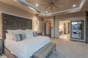 Carpeted bedroom with ceiling fan, ensuite bathroom, and a raised ceiling