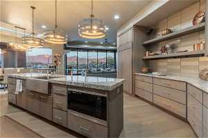 Kitchen with an inviting chandelier, light hardwood / wood-style flooring, an island with sink, backsplash, and stainless steel microwave