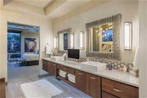 Bathroom with tasteful backsplash, a raised ceiling, double sink vanity, and ceiling fan