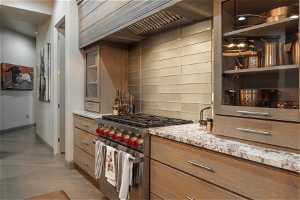 Kitchen featuring tasteful backsplash, designer range, light stone countertops, and light tile floors