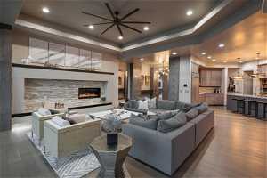 Living room with sink, ceiling fan, a raised ceiling, and hardwood / wood-style flooring