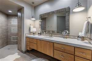 Bathroom featuring tiled shower, oversized vanity, and backsplash