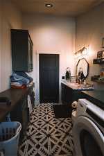 Laundry room/Half Bathroom with a bath to relax in, toilet, vanity, washer / dryer, and tile flooring