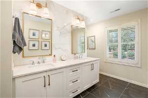 Bathroom with tile floors, double sink, oversized vanity, and plenty of natural light