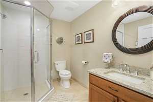 Bathroom with an enclosed shower, vanity, toilet, and tile flooring