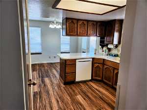 Kitchen with pendant lighting, a chandelier, kitchen peninsula, dark hardwood / wood-style floors, and dishwasher