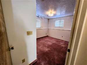 Carpeted spare room with a textured ceiling and track lighting