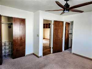 Unfurnished bedroom with dark carpet, a textured ceiling, and ceiling fan