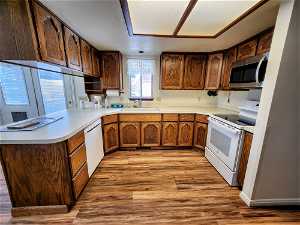 Kitchen with light hardwood / wood-style flooring, sink, white appliances, and kitchen peninsula