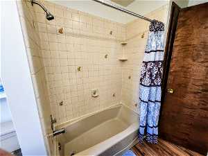 Bathroom with shower / tub combo and hardwood / wood-style floors
