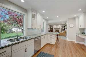 Kitchen featuring plenty of natural light, light hardwood / wood-style floors, dishwasher, and white cabinetry