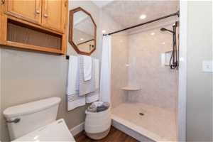 Bathroom featuring walk in shower, toilet, and hardwood / wood-style flooring