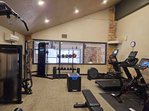 Exercise room featuring a wall mounted AC, vaulted ceiling, and carpet floors