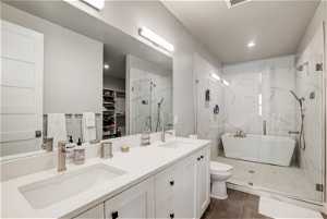 Bathroom featuring tile floors, toilet, a shower with door, and dual bowl vanity