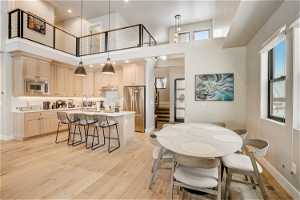 Dining space with a healthy amount of sunlight, a towering ceiling, light hardwood / wood-style floors, and sink