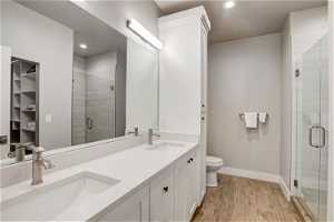 Bathroom with dual bowl vanity, hardwood / wood-style flooring, toilet, and walk in shower