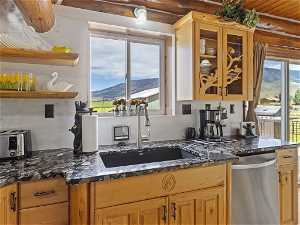Kitchen featuring a mountain view, dishwasher, sink, and dark stone countertops