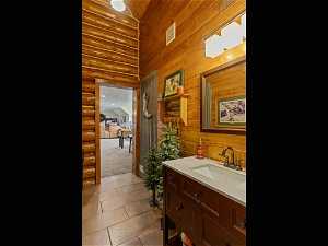 Bathroom with log walls, tile floors, and large vanity
