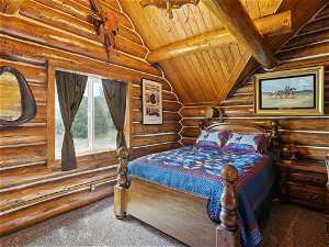 Carpeted bedroom featuring lofted ceiling with beams, log walls, and wood ceiling