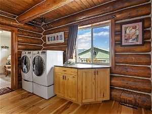 Laundry area featuring rustic walls, cabinets, wooden ceiling, and light hardwood / wood-style floors