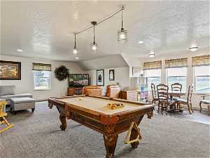 Rec room with lofted ceiling, carpet flooring, billiards, and a textured ceiling