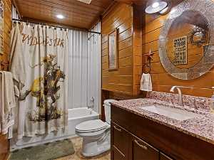Full bathroom featuring wood walls, toilet, shower / bath combo, and oversized vanity