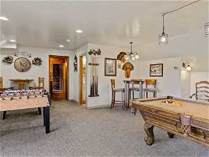 Recreation room with an inviting chandelier, a textured ceiling, pool table, and light carpet