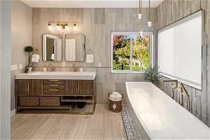 Primary bathroom featuring double vanity, tile walls, tile floors, and a bathing tub