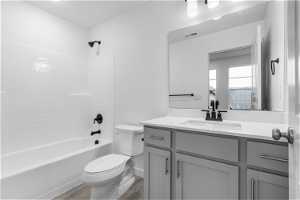Full bathroom featuring hardwood / wood-style flooring, tub / shower combination, toilet, and large vanity