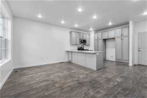 Kitchen featuring gray cabinets, sink, dark wood-type flooring, and kitchen peninsula
