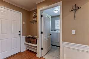 Corridor with ornamental molding, hardwood flooring, laundry room with tile.