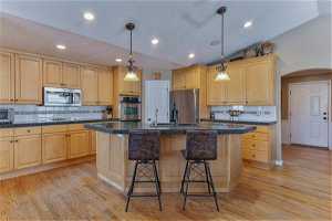 Kitchen featuring a center island, hardwood flooring, pendants, stainless steel appliances, double oven and large pantry.