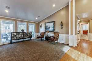 Living room featuring ornamental molding, light hardwood / wood-style floors, ornate columns, and vaulted ceiling