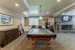 Recreation room with pool table, carpet, a fireplace, and crown molding
